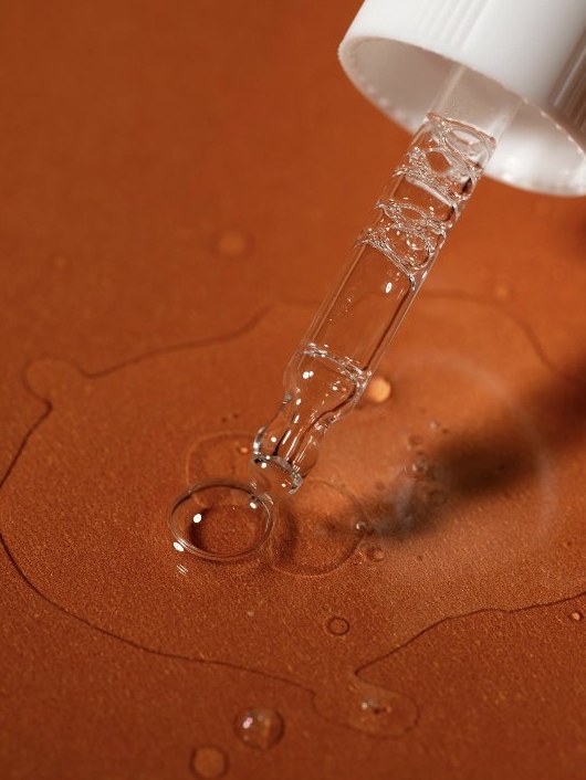 Dropper of ASHRI serum on a terracotta backdrop