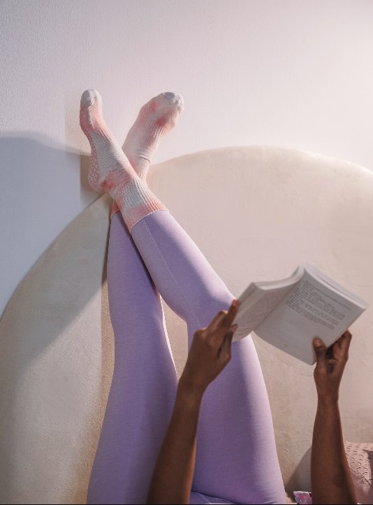 Reading with legs up in lavender leggings and Krump socks