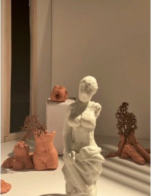 Plaster figure among clay sculptures