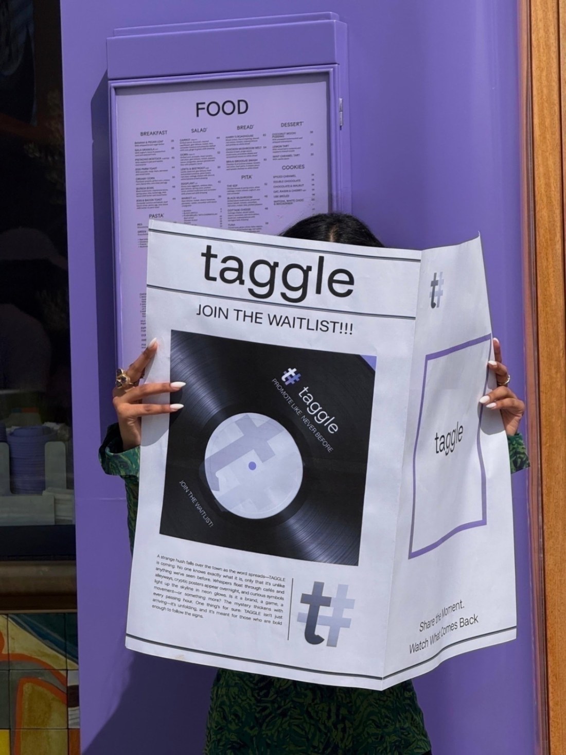 Taggle launch newspaper against a lilac wall
