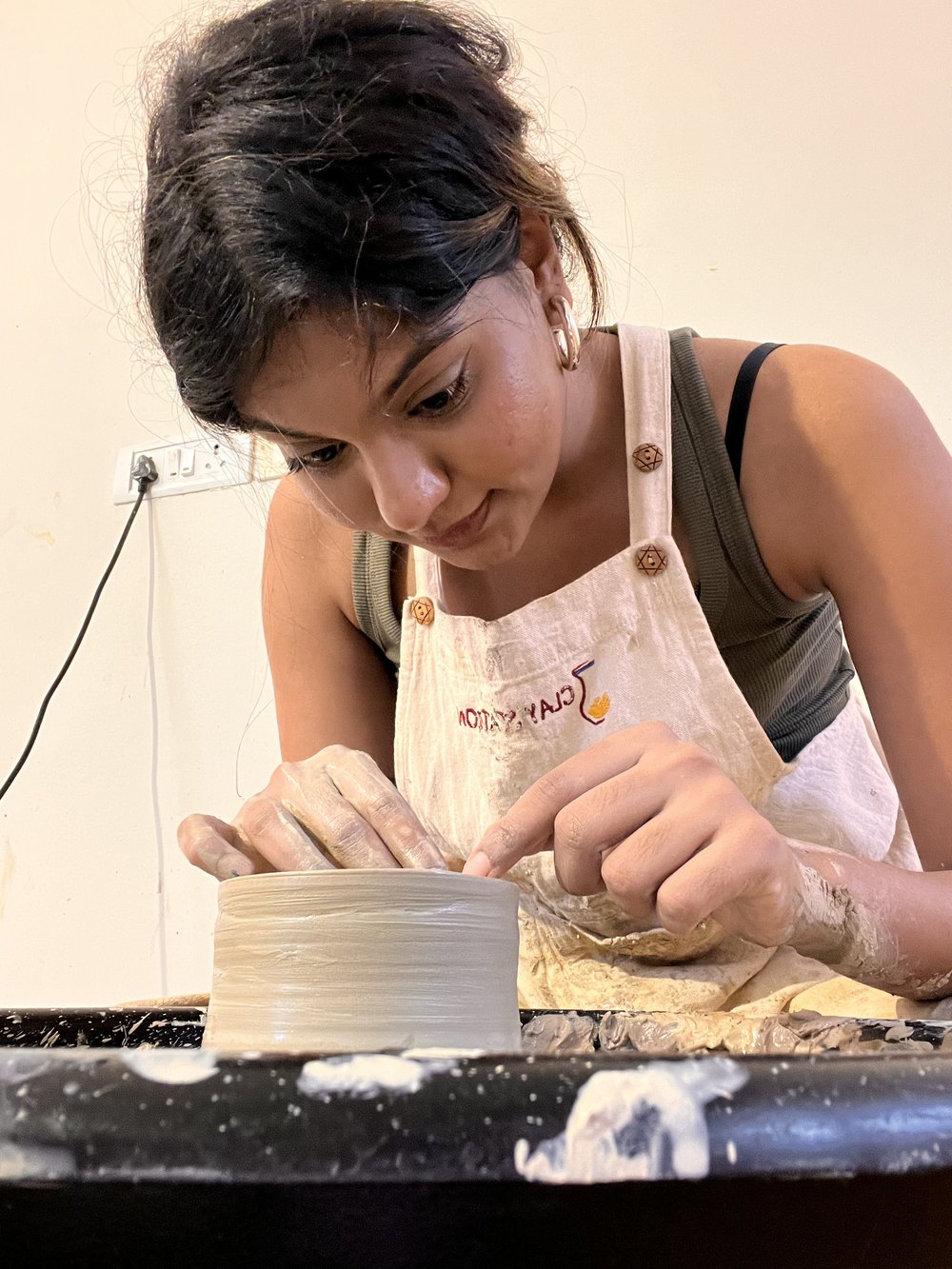Loveleen shaping clay on the pottery wheel